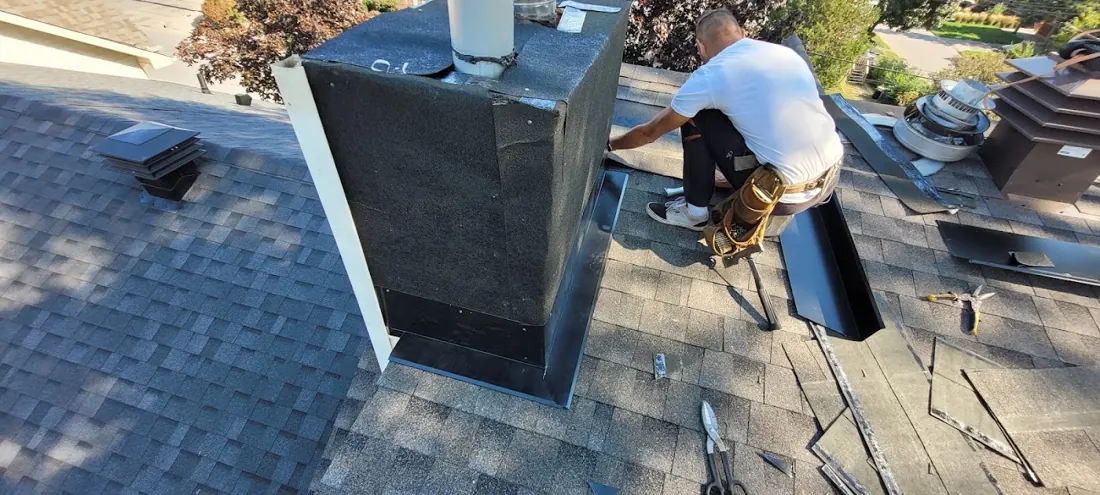 Black chimney cricket being flashed on a roof by a worker